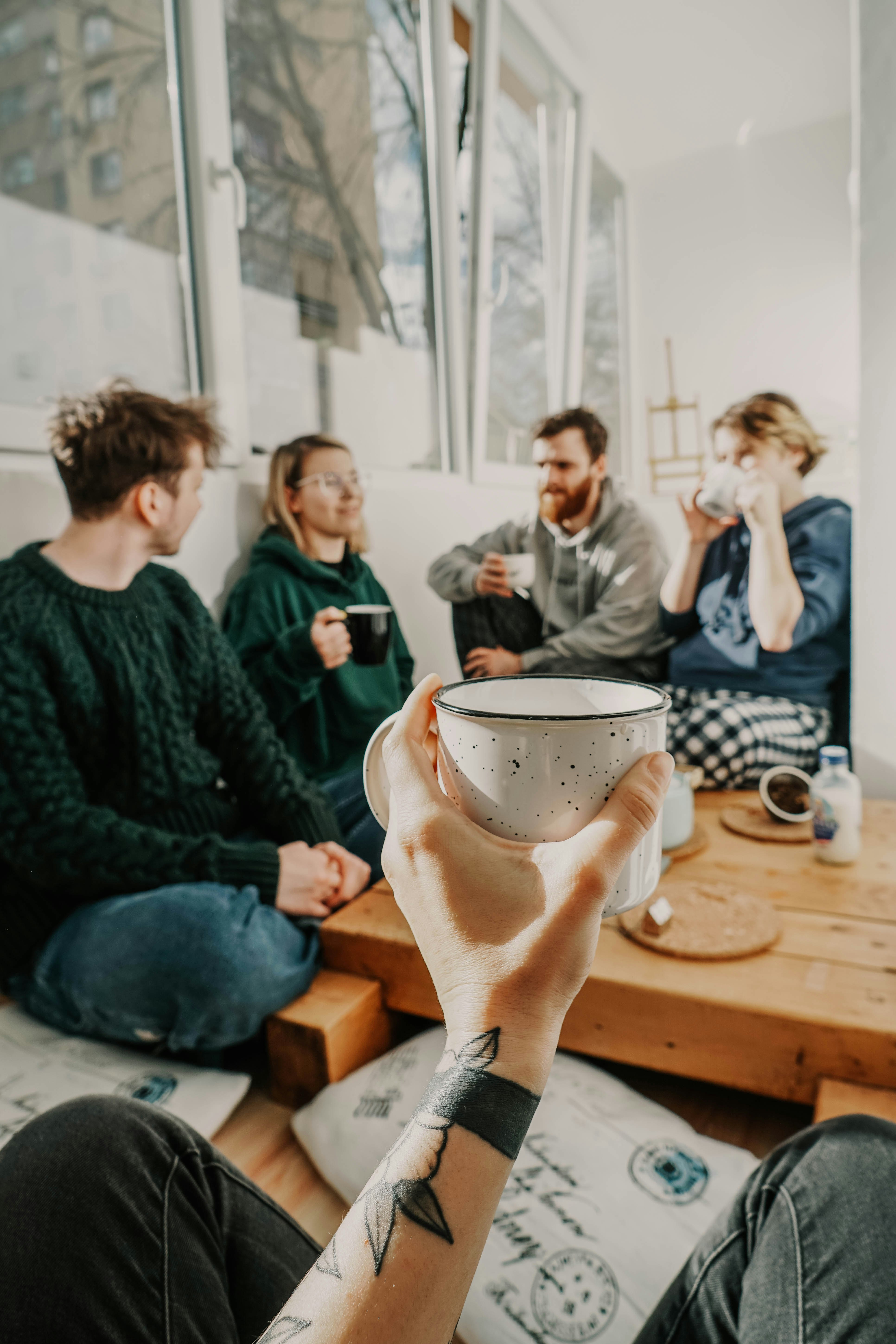 people sitting on chair holding white ceramic mug